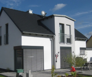 weißes Einfamilienhaus mit dunklem Dach und Raffstore-Blende