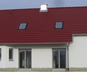 Seitenansicht eines weißen Hauses mit dunkelroten Dach