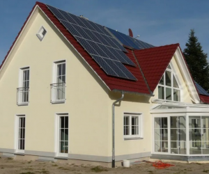 cremefarbenes Haus mit schmalen Fenster, Wintergarten und Solarzellen auf dem Dach