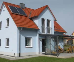 Hellblaues Haus mit rotem Dach und überdachter Terrasse